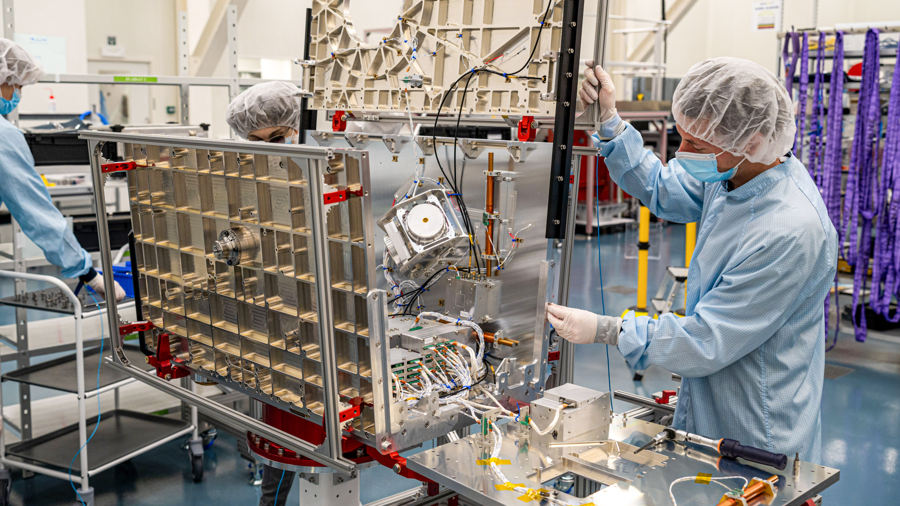 workers in a clean room assemble the satellite