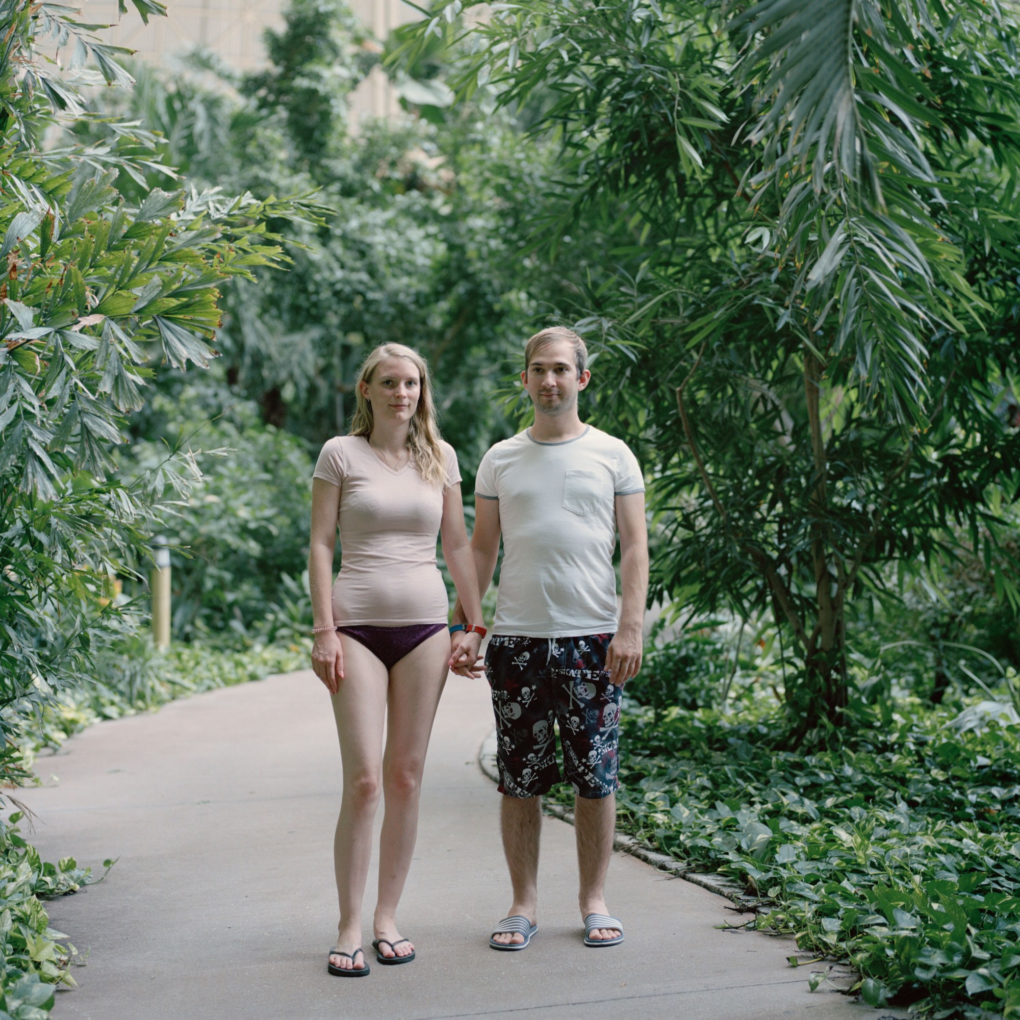 two tourist standing on a path surrounded by tropical foliage