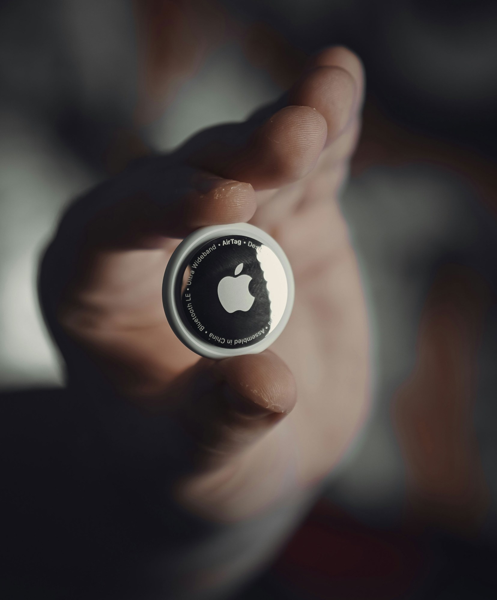 close-up of a hand holding an Apple AirTag